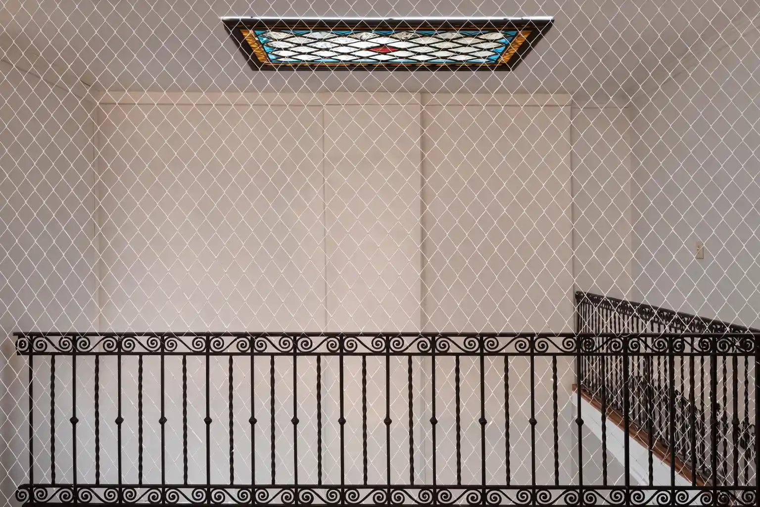 Red de protección en escalera interior con vitral